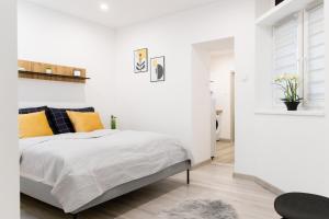 什图罗沃The Central Border Premium Apartment的卧室拥有白色的墙壁,配有带橙色枕头的床。