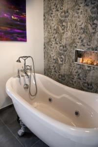 费拉拉Boutique Hotel Ferrara的配有白色浴缸的带绘画的浴室