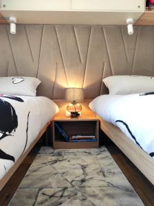 德拉格Zen Zone Premium Mobile Home的一间卧室配有两张床和一个带灯的床头柜