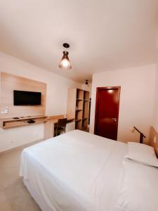 圣塞巴斯蒂安Abricó Beach Hotel的卧室配有白色的床和平面电视。