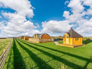 威克Caithness View Luxury Farm Lodges and BBQ Huts的一片宽阔的草地,远处有一座建筑