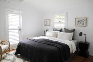 拜伦湾Sirens的白色卧室设有一张大床和两个窗户