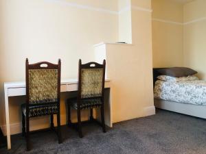 罗奇福德AC Lounge 119的一间卧室配有两把椅子、一张桌子和一张床