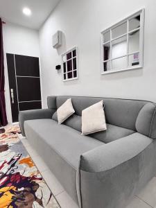 亚娄RAINA MUSLIM FRIENDLY HOMESTAY Perlis的客厅里设有一张灰色沙发,客厅里设有窗户