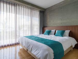 读谷村Bosco Yomitan Resort Condminium的一间卧室设有一张大床和大窗户