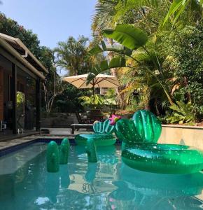 拜伦湾Beach Jungle - Hot Tub, Firepit & Pool in Beachside Oasis的庭院内带绿色充气椅的游泳池