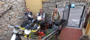 奥尔戈索洛b&b il Portico Orgosolo的三个人站在一个门前,骑着摩托车