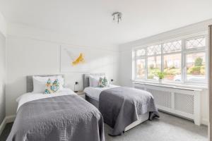 BansteadSurrey Stays - 4 bedroom house, sleeps 9, 2 bathrooms, CR5, near Gatwick Airport的一间白色卧室,配有两张床和窗户