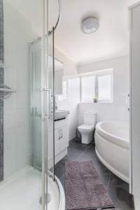 BansteadSurrey Stays - 4 bedroom house, sleeps 9, 2 bathrooms, CR5, near Gatwick Airport的白色的浴室设有浴缸、卫生间和水槽。