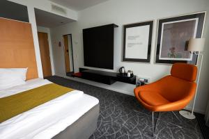 尼堡Nyborg Strand Hotel & Konference的配有一张床和一把椅子的酒店客房