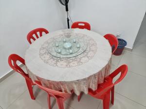 山打根Sweethome Homestay Sandakan的一张带红色椅子的白色桌子和盘子