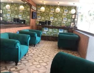 拉合尔Lotus One Hotel的餐厅里带绿椅的等候室