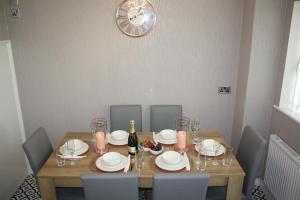 布莱奇利Gorgeous 3 bed House In Bletchley Milton Keynes的餐桌、椅子和墙上的时钟