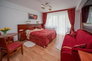 雅罗斯瓦维茨Aquapark Health Resort & Medical SPA Panorama Morska All Inclusive的一间卧室配有红色的床和桌椅
