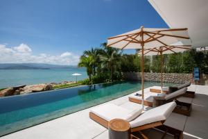 苏梅岛Kerem Luxury Beachfront Villas的一个带两把椅子和遮阳伞的游泳池