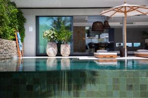 苏梅岛Kerem Luxury Beachfront Villas的一个带两瓶花和一把遮阳伞的游泳池