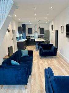 切尔滕纳姆Stunning modern 2 bedroom, 2 bathroom townhouse的一间带2张蓝色沙发的客厅和一间厨房