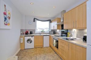 阿伯丁Caledonia Newhills Apartment的厨房配有木制橱柜、洗衣机和烘干机