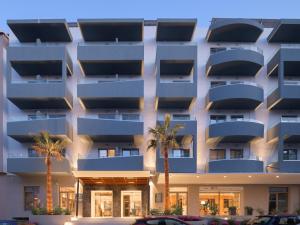 罗希姆诺Bio Suites Hotel & Spa的公寓大楼前方有棕榈树