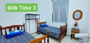 马六甲Homestay Intan Anjung Lodge的卧室设有两张单人床,配有3名词条计费师