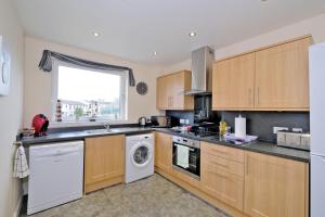 阿伯丁Caledonia Netherhills Apartment的厨房配有木制橱柜、洗衣机和烘干机