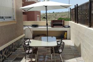 阿利坎特adosado con piscina a 10 minutos de Alicante的阳台上配有白色桌椅和遮阳伞
