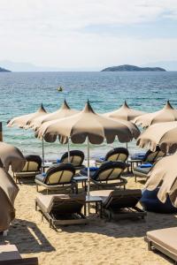 梅加利阿莫斯Skiathos Thalassa Cape, Philian Hotels and Resorts的海滩上的一组椅子和遮阳伞