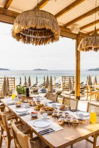 梅加利阿莫斯Skiathos Thalassa Cape, Philian Hotels and Resorts的海滩上一张长木桌,上面有食物