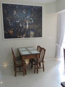 巴拉奈里奥-坎布里乌Apartamento Coral - 1 quadra do Mar的一张餐桌,配有两把椅子和一幅画