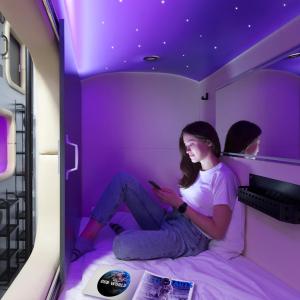 利沃夫Capsule Hotel Constellation 89的坐在紫色房间床中的女人