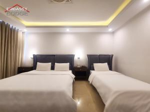 伊斯兰堡Embassy Lodge的配有白色床单的酒店客房内的两张床