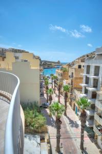 克伦蒂Seaside apartment in the heart of Xlendi Gozo的阳台享有棕榈树街道的景色。