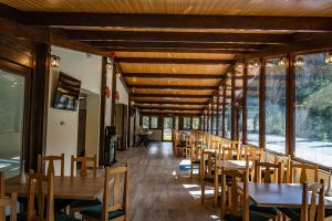 阿列谢尼PENSIUNEA SKY HUB的餐厅设有木桌、椅子和窗户。