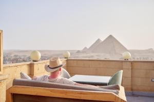 开罗Gardenia Apartment Pyramids View的坐在金字塔床里的牛仔帽上的男人