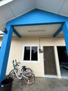 Kampong Ru SepulohMahasa Penarik Homestay的停在有蓝色屋顶的房子外的自行车