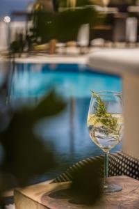 凯米Griffon Kymi Hotel previously known as Valledi Village的坐在游泳池畔的桌子上喝一杯葡萄酒