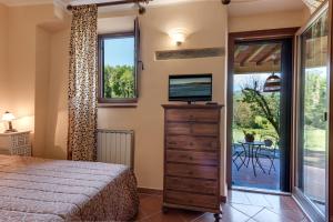 梅里托Villa Poggio Di Gaville的一间卧室配有一张床、一台电视和一个窗口