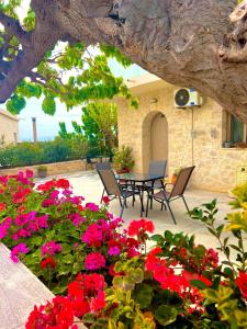 基萨莫斯Poseidon Apartments的一个带红色鲜花和桌椅的庭院