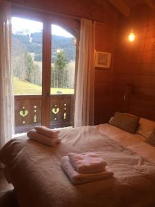 莱热Chalet Pierre, Les Gets的一间卧室配有一张带毛巾的床和窗户。