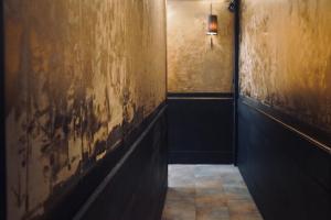 奈梅亨B&B Noviomagus的暗走廊上设有一面墙面,上面有剥落的油漆