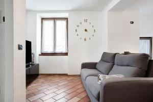 滕诺Appartamento nel cuore di Tenno的客厅配有沙发和墙上的时钟