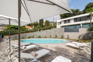 丰沙尔CASA DO MIRADOURO 5 by Heart of Funchal的一个带白色椅子和遮阳伞的游泳池