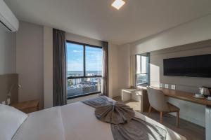 里奥格兰德Hotel Laghetto Rio Grande的一间卧室配有一张床、一张书桌和一个大窗户