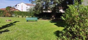 PéronnasStudio au calme的坐在院子里草地上的绿色长凳
