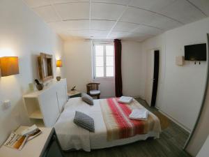 比亚里茨小酒店的一间卧室配有一张床、一张书桌和一个窗户。