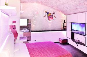 普蒂尼亚诺l'angolo di Gaudì, alcoba Capriccio的一间卧室配有粉红色的床和电视