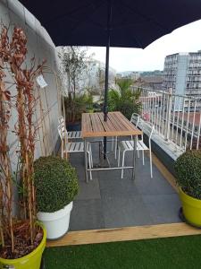 列日Liège centre Médiacité appartement parking gratuit terrasse immense 8ème pour 2 personnes的阳台上配有一张木桌子和椅子,阳台配有遮阳伞