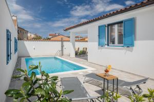 佩罗杰Spacious holiday house in Istria的一座带蓝色百叶窗的房屋后院的游泳池