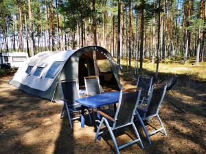 GräsmarkVolledig ingerichte tent op natuurcamping的帐篷前的桌椅