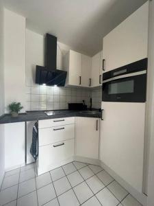 开姆尼茨Modernes Apartment in Chemnitz的厨房配有白色橱柜和黑色用具